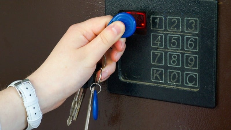 Featured image: Hand holding key fob with keys on key chain scanning outside number panel security access  - Read full post: Adding Security Access to a Building